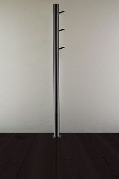 a tall metal pole sitting on top of a wooden floor next to a white wall