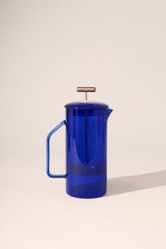 a blue glass coffee pot with a wooden handle on a white background, it appears to be empty