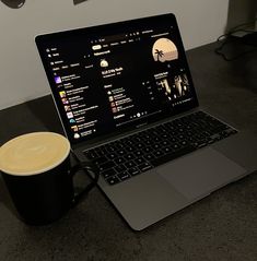 an open laptop computer sitting on top of a table next to a cup of coffee