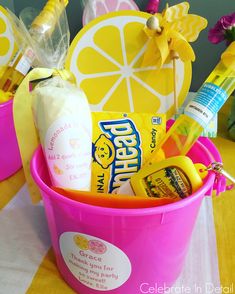 a pink bucket filled with personal care items on top of a yellow and white table cloth