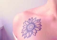 a woman's shoulder with a sunflower tattoo on her left arm and chest