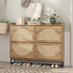 a wooden cabinet with baskets and shoes on top of it next to a wall mounted clock