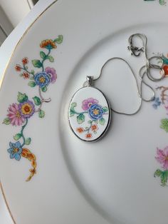 a close up of a plate with a keychain on it and flowers painted on the side