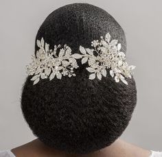 the back of a woman's head wearing a hair comb with flowers and leaves on it