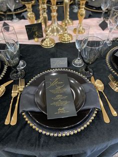 the table is set with black and gold place settings