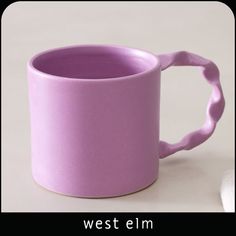 a purple coffee cup sitting on top of a white table