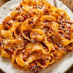 pasta with meat sauce and parmesan cheese on a white plate next to a fork