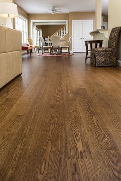 a living room with hard wood flooring and furniture in the background at an open concept home