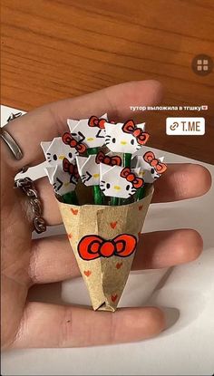 a hand holding an origami cone with hello kitty decorations on it's side