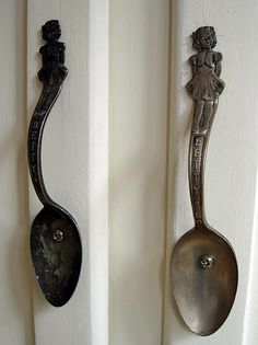 two spoons hanging from the side of a white door, one with an image of a woman on it