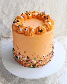 an orange frosted cake with sprinkles and eyes