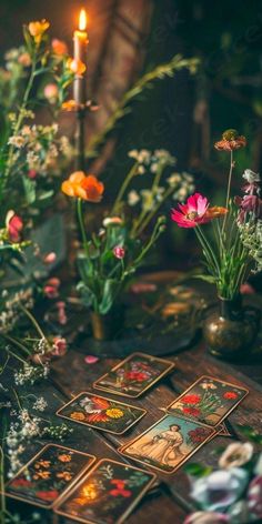 a table topped with lots of flowers and cards next to a lit candle on top of it