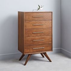 a wooden chest of drawers in a room with grey walls and white carpeted flooring