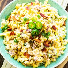 a blue bowl filled with macaroni salad on top of a wooden table