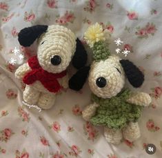 two small crocheted dogs sitting next to each other on a floral bed sheet