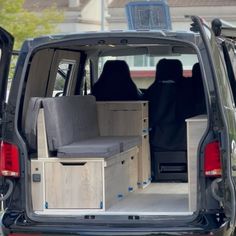 the back end of a van with its doors open and two seats folded up in front