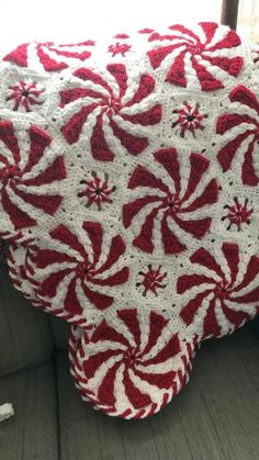 a red and white crocheted blanket sitting on top of a couch