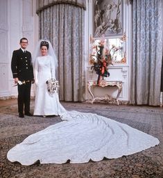 a bride and groom standing in front of a large white wedding dress on the floor