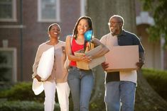 three people carrying boxes and smiling at the camera