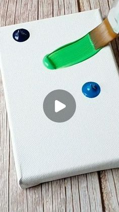 an image of a paintbrush painting the bottom of a canvas with blue and green buttons