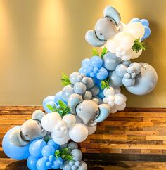 an elephant balloon arch with blue and white balloons hanging from it's sides on a wooden floor