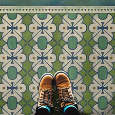 a person standing on a tiled floor with their feet up in front of the camera