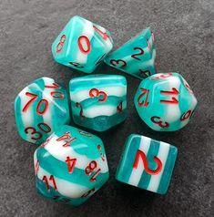 seven turquoise and white dice with red numbers on the sides, sitting on a gray surface