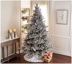 a decorated christmas tree in a living room with presents on the floor next to it