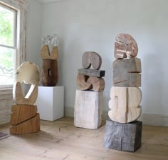 three wooden sculptures sitting on top of a hard wood floor next to an open window