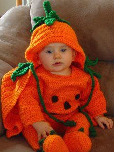 a baby in an orange knitted pumpkin outfit