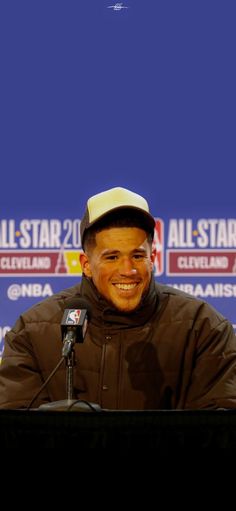 a smiling man sitting at a microphone in front of a blue screen with the words all - star on it