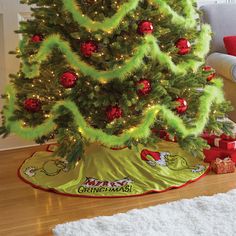 a green christmas tree with red ornaments on it's base and presents under the tree