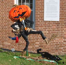 a statue of a man dressed as a jack - o'- lantern is in front of a brick building