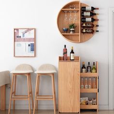 two stools in front of a wine rack with bottles and glasses on it next to a bar