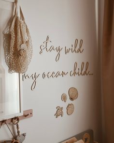 there is a sign on the wall that says stay wild, my ocean child and seashells