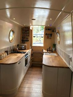 a narrow galley kitchen with wooden counter tops and white cabinets, along with an open window