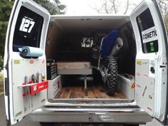 the back end of a white van with an atv in it's cargo area