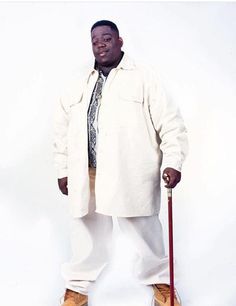 a man in white coat and tie standing with skis on his feet while holding a cane