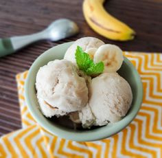 two scoops of ice cream in a bowl with banana slices and mint on top