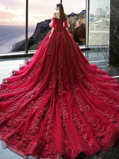 a woman standing in front of a window wearing a red dress with sleeves and flowers on it