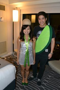 a man and woman standing next to each other in a hotel room with a green leaf costume on