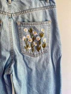 a pair of jeans with daisies embroidered on them