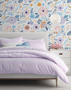 a bedroom with floral wallpaper and bedding in pastel colors, including pink