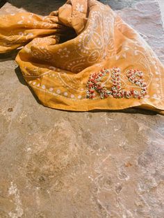 an orange scarf laying on top of a stone floor