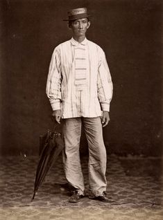 an old black and white photo of a man in a hat standing with an umbrella