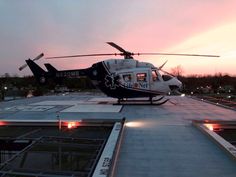 a helicopter sitting on top of an airport tarmac next to another plane at sunset