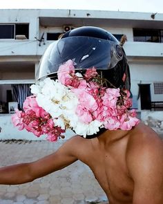 a man wearing a helmet with flowers on it's face and his hand out to the side