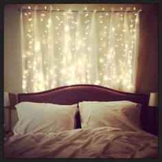 an image of a bed with lights on the headboard and curtains in the background