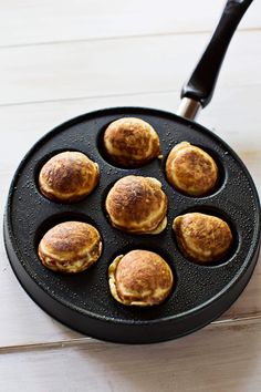 six pancakes in a pan with a spatula next to them on a white table