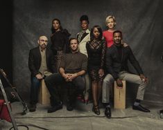 a group of people sitting next to each other in front of a black background with a microphone